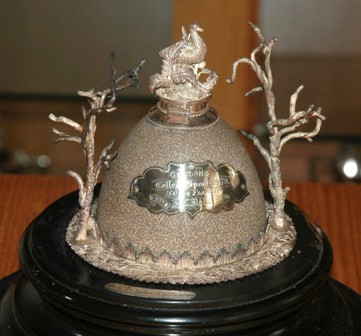 Masters Trophy, 1878 (150 yard sprint) won by J C Bell Made by Fischer, this trophy was provided by W B Haines and consists of half an emu egg mounted in silver on a black stand and having at the top a hinged ink-pot surmounted by a silver emu. The whole is covered by a glass dome. This trophy was bequeathed to the School in 1981 by the daughter of J C Bell of Woodbrook, Teesdale - M K A Bell of Bellbrae.